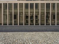 this is an old fashioned stone path outside a tall building with glass windows and doors