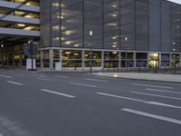 an empty street with some buildings and no traffic at night as seen from across the street