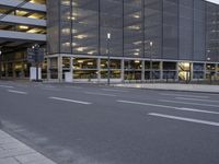 an empty street with some buildings and no traffic at night as seen from across the street