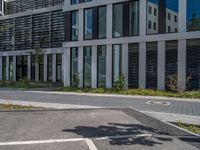 a person is riding a motorcycle on the pavement by some buildings and trees outside of a large building