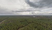 an aerial view of the landscape under grey skies and clouds with trees and farms across a farm land