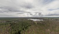 an aerial view of the landscape under grey skies and clouds with trees and farms across a farm land