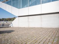 a bike leans against the edge of a brick walkway near a white building in a city