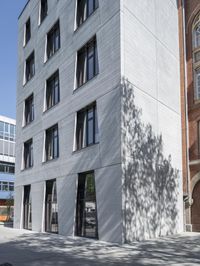 a tall building with a clock on top of it's outside walls next to a street with cars and pedestrians