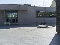 the empty bench is in front of the building that's being used by a bicycle