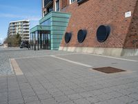 a brick wall with three round vents on it, outside of a building and there is an entrance way through it