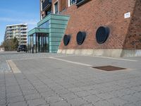 a brick wall with three round vents on it, outside of a building and there is an entrance way through it