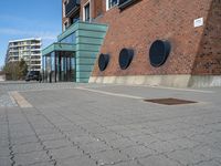 a brick wall with three round vents on it, outside of a building and there is an entrance way through it