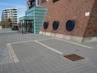 a brick wall with three round vents on it, outside of a building and there is an entrance way through it