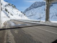an empty road with mountains in the back ground in the background covered with snow and snow