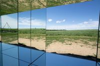 reflection of a body of water and hills in mirrors on display at a museum or cultural center