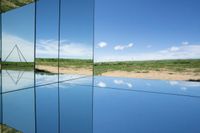 reflection of a body of water and hills in mirrors on display at a museum or cultural center