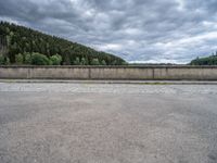 concrete walkway with trees and fenced in area on opposite sides of the road and one side of the road