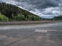 concrete walkway with trees and fenced in area on opposite sides of the road and one side of the road