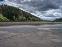 concrete walkway with trees and fenced in area on opposite sides of the road and one side of the road