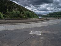 concrete walkway with trees and fenced in area on opposite sides of the road and one side of the road