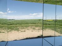 a view from inside of a glass enclosure looking out on wind turbines and the blue sky