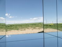 a view from inside of a glass enclosure looking out on wind turbines and the blue sky