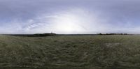 a wide panoramic photo of a grassy meadow, with a castle in the distance