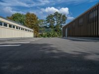 a metal building with a corrugated door in front of it and trees lining the street behind it