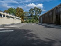 a metal building with a corrugated door in front of it and trees lining the street behind it