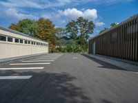 a metal building with a corrugated door in front of it and trees lining the street behind it