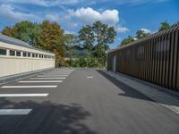 a metal building with a corrugated door in front of it and trees lining the street behind it