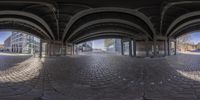 a fish eye shot of a modern building surrounded by arches and bricks in a town