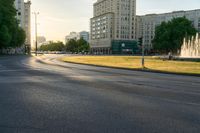 a traffic light sitting next to a city street next to tall buildings on either side of an empty field