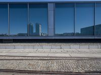 there is a building and some rails next to it, along with the reflection of another building in a window