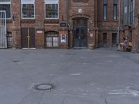 a man sitting in front of an empty building with an outside seating area next to it