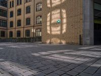 a brick courtyard has steps leading up to it, and a blue umbrella is on the ground