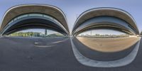 multiple curved windows reflecting the sun on the outside and into it, and some buildings in the background