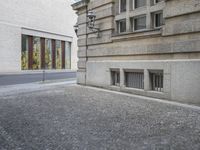 an empty cobblestone street is shown with a fire hydrant nearby it, along with a bricked building behind it