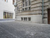 an empty cobblestone street is shown with a fire hydrant nearby it, along with a bricked building behind it