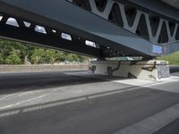 a man with a skateboard is walking under a bridge with graffiti on it's sides