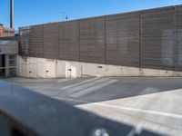 a man skateboarding in an enclosed parking garage area by a fenced off walkway