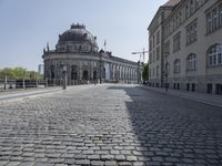 a large stone road leads down from a large building with a dome in the center