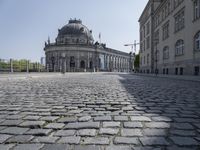 a large stone road leads down from a large building with a dome in the center