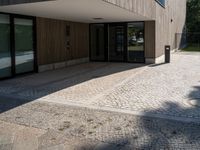 a building that has a glass door on it next to a brick sidewalk that is between trees