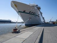 a man sits under a large cruise ship at the dock's entrance pier by himself