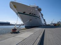 a man sits under a large cruise ship at the dock's entrance pier by himself