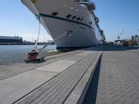 a man sits under a large cruise ship at the dock's entrance pier by himself