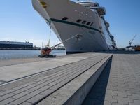 a man sits under a large cruise ship at the dock's entrance pier by himself