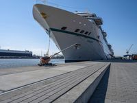 a man sits under a large cruise ship at the dock's entrance pier by himself