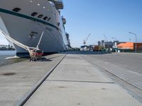 a man sits under a large cruise ship at the dock's entrance pier by himself