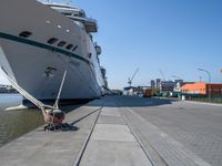 a man sits under a large cruise ship at the dock's entrance pier by himself