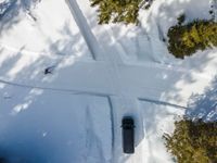 an overhead view of a snow slope with a car going over the slope near trees