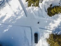 an overhead view of a snow slope with a car going over the slope near trees