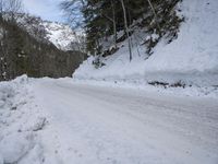 a snow - covered road in the middle of some trees and a snowy hill side
